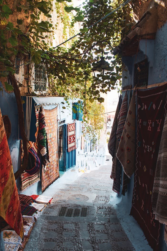 Picturesque narrow alley with vibrant rugs in the blue city of Chefchaouen, Morocco.