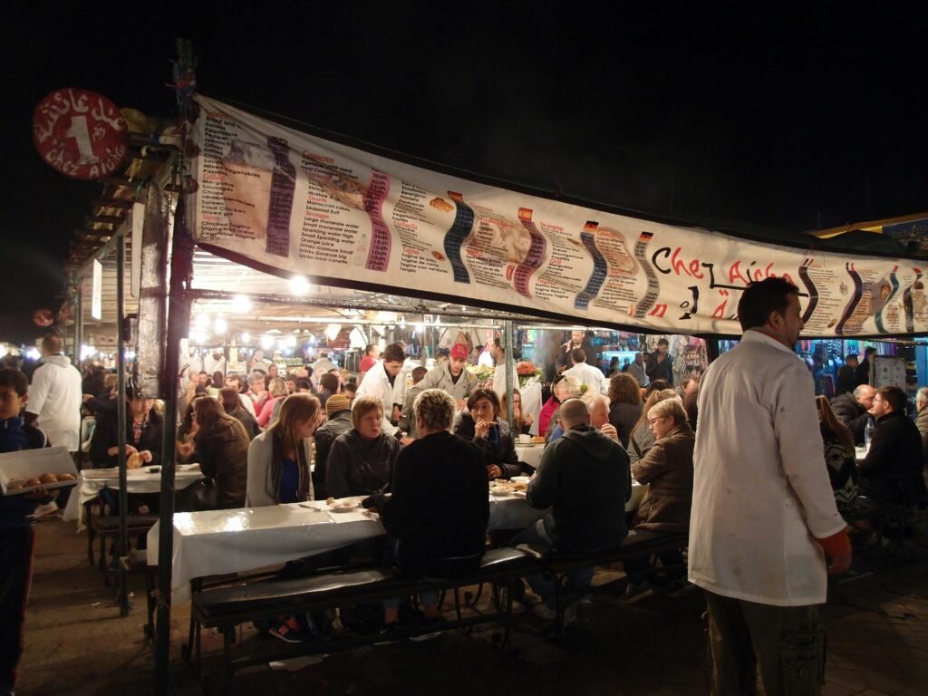 Crowded dining scene at an outdoor market in Morocco, showcasing lively nightlife and cultural interactions.