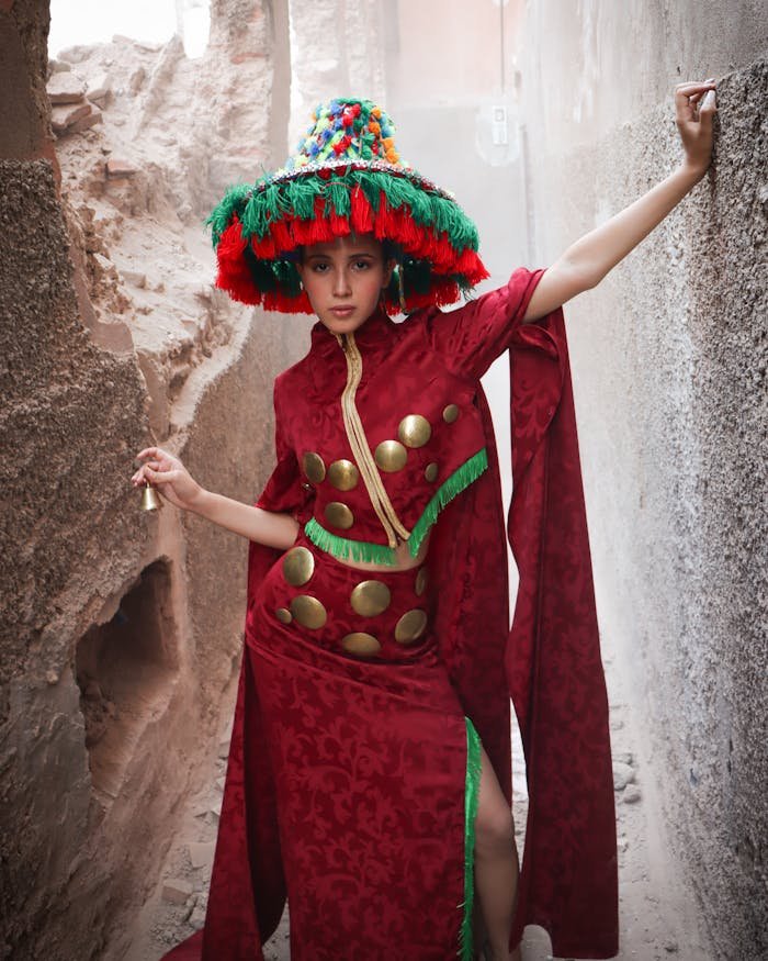 Woman in vibrant traditional Moroccan dress posing in a narrow alleyway in Marrakesh.
